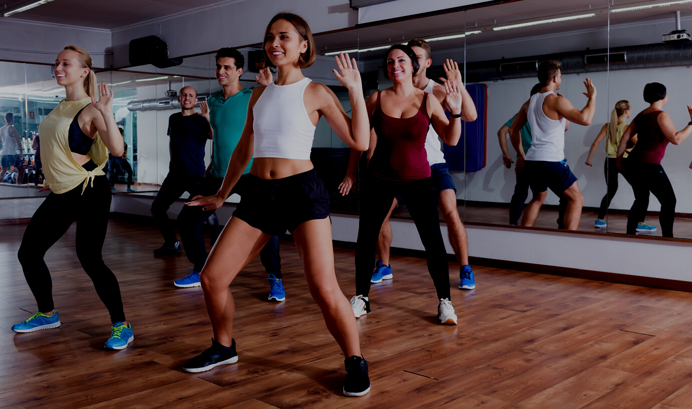 Young happy dansers studying zumba elements